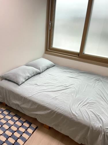 a bed with two pillows in a room with a window at Danaharu Guesthouse in Jeonju