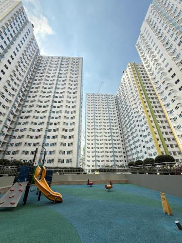 a playground in front of two large white buildings at MPlace Tower D Condo Unit in Manila