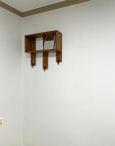 a wooden shelf on the wall of a white wall at Danaharu Guesthouse in Jeonju