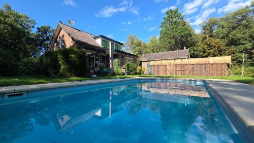 a swimming pool in front of a house at Villa in the forest of Amsterdam with Pool in Velsen-Zuid