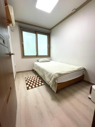 a small bedroom with a bed and a window at Danaharu Guesthouse in Jeonju