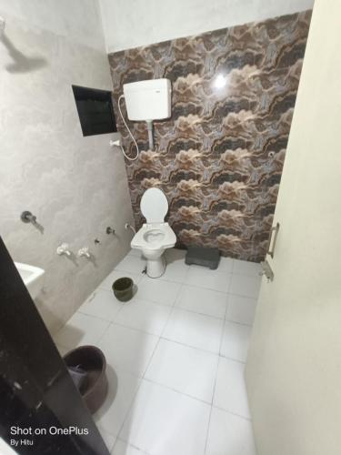 a bathroom with a toilet and a stone wall at Kuber palace in Dwarka