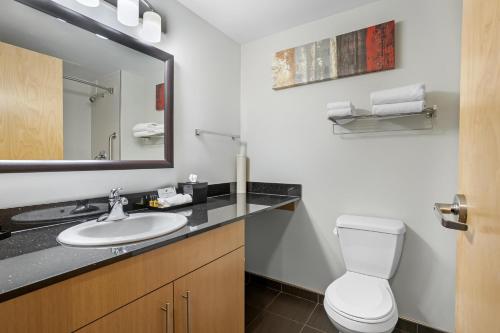 a bathroom with a sink and a toilet and a mirror at Best Western Plus Airport Inn & Suites in Saskatoon