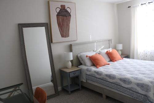 a bedroom with a bed with orange pillows and a mirror at One bedroom condo close to H St in Washington