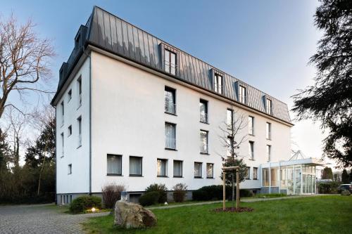 a white building with a black roof at Garner Hotel Cologne East by IHG in Cologne