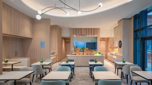 a restaurant with tables and chairs and a counter at Holiday Inn Express Haikou Int'l Duty Free City by IHG in Haikou