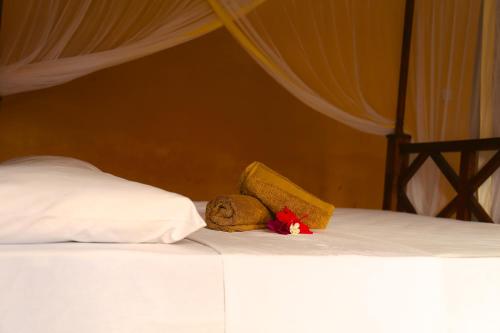a bed with a pillow and a stuffed animal on it at Kigwedeni Villas in Nungwi