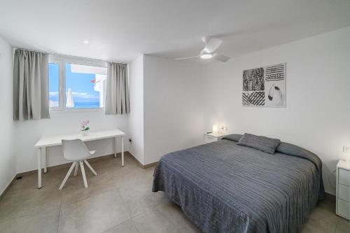 ein Schlafzimmer mit Bett, Schreibtisch und Fenster in der Unterkunft Magnífico Bungalow con Vista Panorámica y Piscina Privada in Acantilado de los Gigantes