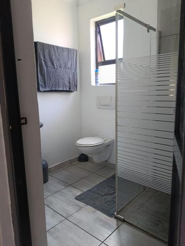 a bathroom with a toilet and a glass shower at Richards Bay Stay in Richards Bay