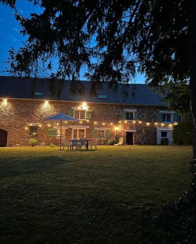 a brick house with a picnic table in the yard at night at Grande maison avec piscine 13 couchages proche Paris in Rebais
