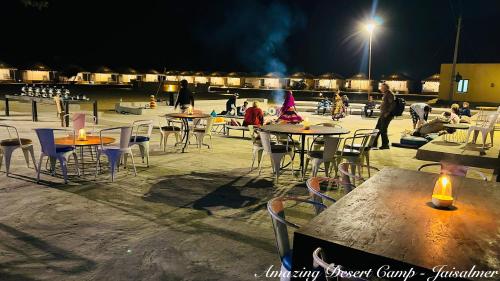 a group of tables and chairs with people at night at Amazing Desert Camp in Jaisalmer