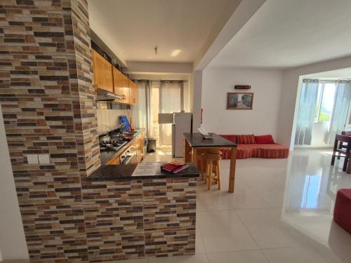 a kitchen and living room with a brick wall at Apart Laginha Tess & To in Mindelo