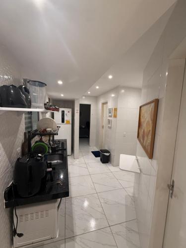 a room with a kitchen with a counter and a hallway at Cantinho Aconchegante- Quarto 03 Família - com AR in Bayeux