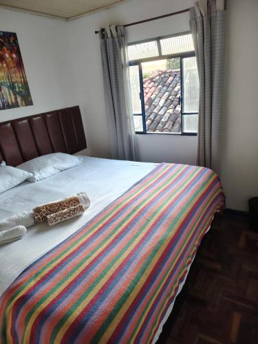 a bed with a colorful blanket on it with a window at Casinha próxima a Praça Tiradentes in Ouro Preto