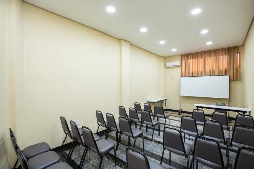 a conference room with chairs and a white screen at Hotel Suárez São Leopoldo in São Leopoldo