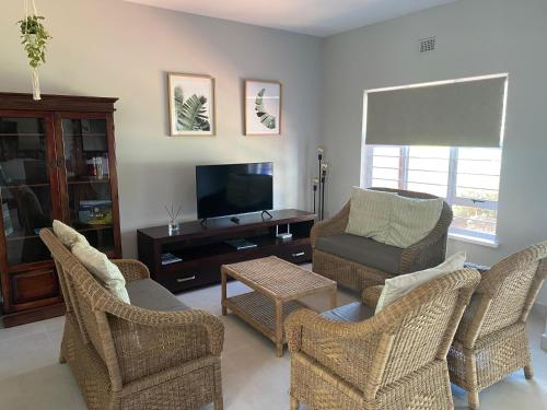a living room with wicker chairs and a flat screen tv at 4 La Toinette in Ballito