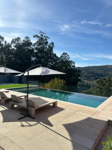 a swimming pool with an umbrella and two lounge chairs and a swimming pool at Bem Viver Country House in Favões