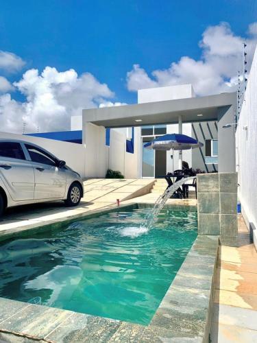 a car parked in front of a house with a fountain at Casa Almar Carapibus in Conde