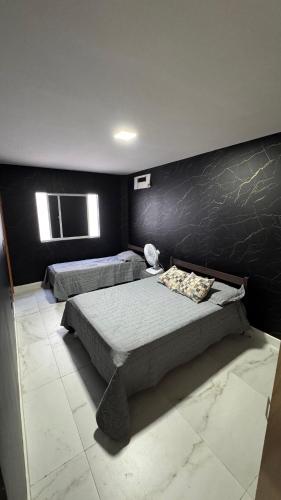 a bedroom with two beds and a black wall at Casa Almar Carapibus in Conde