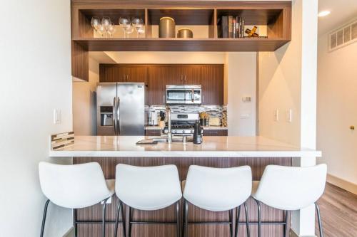 a kitchen with a bar with four white bar stools at Trendy 2BD 2BTH Apt steps from Downtown Santa Monica! in Los Angeles