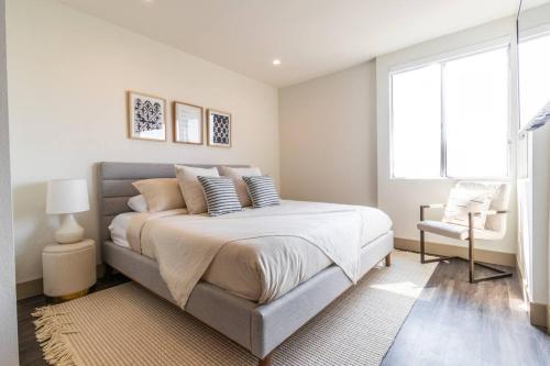 a white bedroom with a large bed and a chair at Trendy 2BD 2BTH Apt steps from Downtown Santa Monica! in Los Angeles