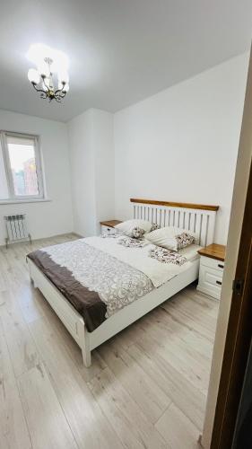 - une chambre blanche avec un grand lit et un lustre dans l'établissement ЖК Асель, à Atyraū