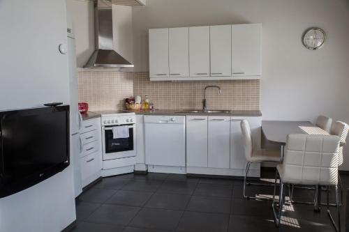 a kitchen with white cabinets and a table with chairs at Holiday Linnunlahti in Joensuu