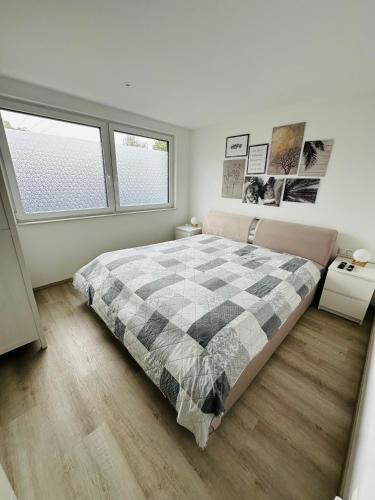 a bedroom with a large bed and two windows at FerienWohnung Gästehaus Merzig-Besseringen NEUBAU in Merzig