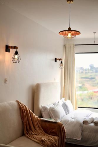 a bedroom with a bed and a couch and a window at Eloura Homes Stanley Studio in Kiambu