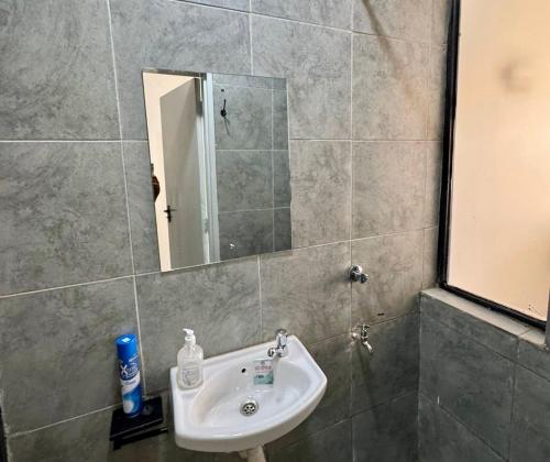 a bathroom with a sink and a mirror at Eloura Homes Stanley Studio in Kiambu