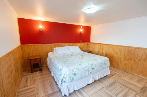 a bedroom with a bed and a red wall at Hostal Andes Patagónicos in Puerto Natales