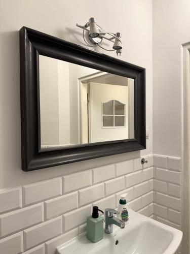 a bathroom with a mirror and a sink at Justinrent Piekarska in Legnica
