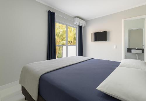 a white bedroom with a large bed and a window at Alto Padrão 5 Stes +1 apoio Piscina quente+Jacuzzi in Praia Guaratuba