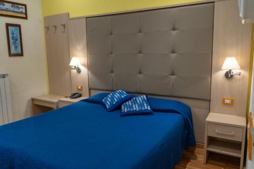 a bedroom with a blue bed with a large headboard at Hotel Alexander & Spa in Sanremo