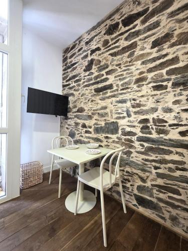 a table and chairs in front of a stone wall at Estudio Casco Histórico Betanzos in Betanzos