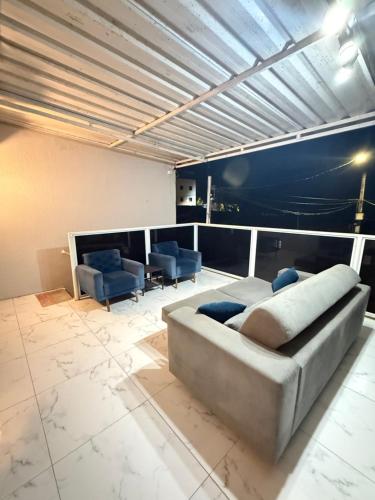 a living room with a couch and blue chairs at Cantinho Aconhegante - Quarto 07 AR-condicionado in Bayeux