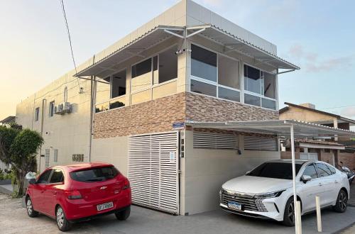 two cars parked in front of a house at Cantinho Aconhegante - Quarto 07 AR-condicionado in Bayeux