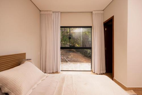 a bedroom with a bed and a large window at @Stay22 - Sítio Ypê Amarelo /Alto padrão - Luxuoso in São Lourenço