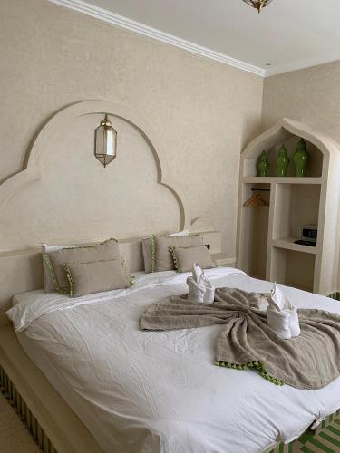 a bedroom with a large white bed with an arched headboard at Merzouga Hous in Merzouga