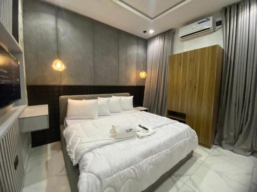 a bedroom with a large white bed with a phone on it at Cozy Corner Apartments in Lekki