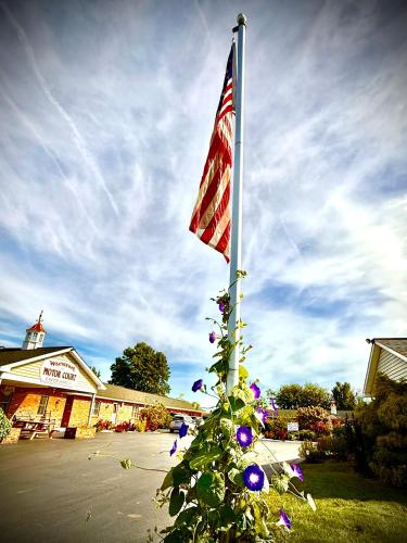 a flag on a pole with flowers in front of a building at Weathervane Motor Court in Ronks