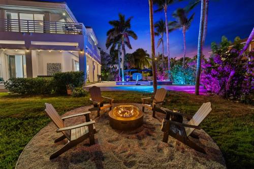 a group of chairs around a fire pit in front of a house at Villa Harrison . in Hollywood Beach