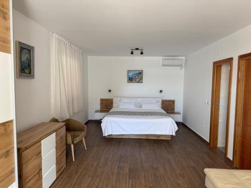 a white bedroom with a bed and a chair at VILLA V&D in Milna