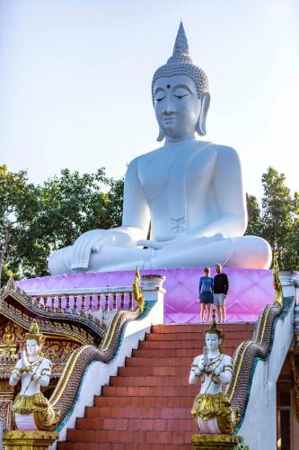 a giant buddha statue with people standing on the stairs at Kanlaya's Eyrie, Luxury Homestay in Pang Mapha