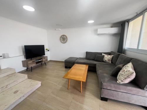 a living room with a couch and a tv at Sea Breeze Oasis in Eilat