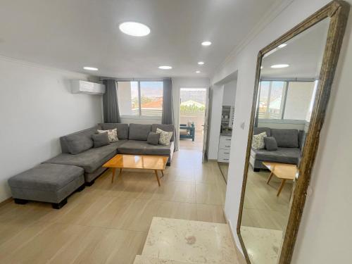 a living room with a couch and a mirror at Sea Breeze Oasis in Eilat