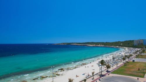 uma vista para uma praia com pessoas e para o oceano em Hipotels Flamenco em Cala Millor