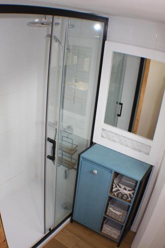 a bathroom with a shower with a blue cabinet and a mirror at La maison verte in Arreau