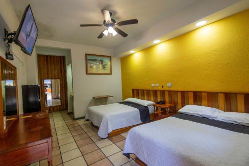 a hotel room with two beds and a ceiling fan at Hotel Lacantum in San José
