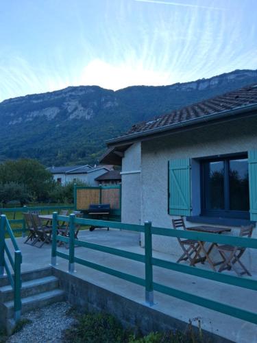 a house with a deck with mountains in the background at Le Lodge Arthur Appartement 8 personnes in Barraux